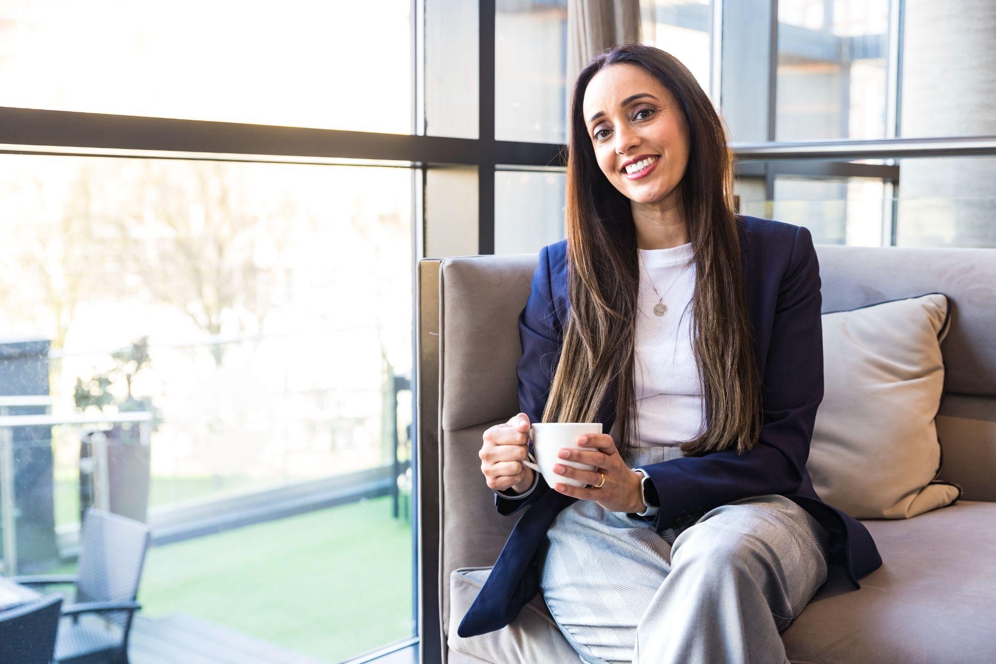 Smiling woman sitting on a sofa holding a cup