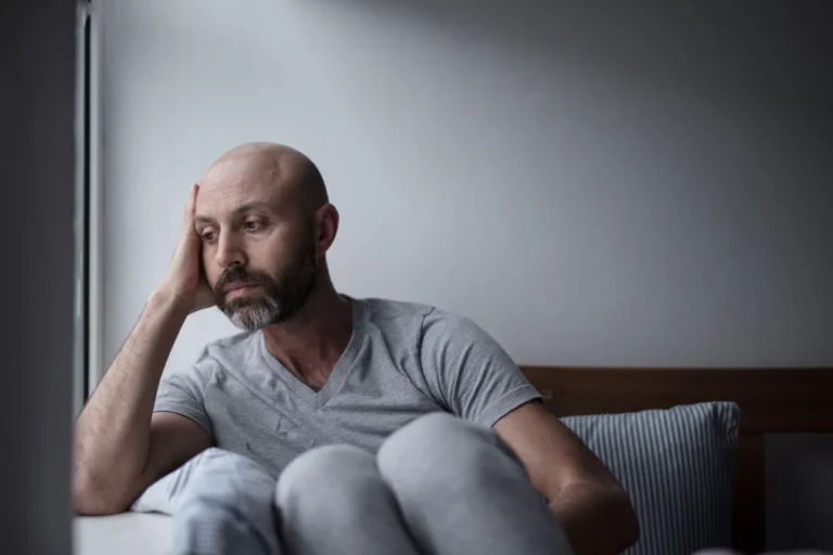 Man sitting on a sofa looking stressed and withdrawn