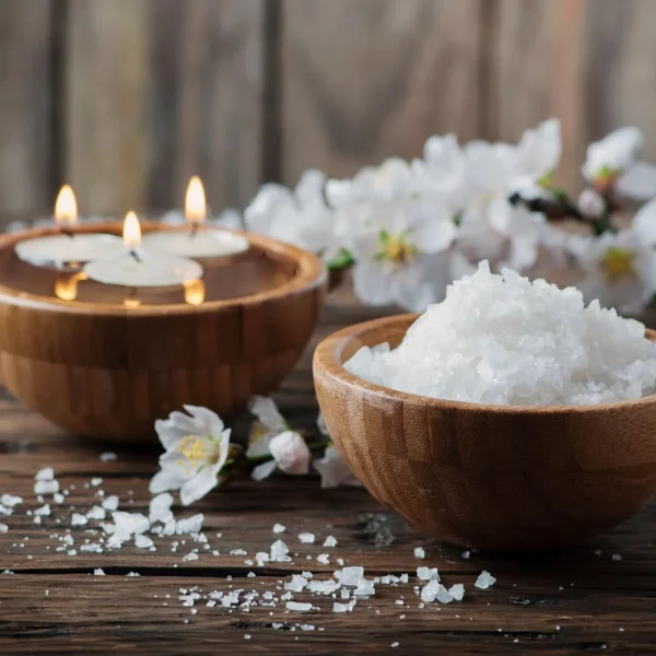 Floating candles and bath salts in wooden bowls with white blossom